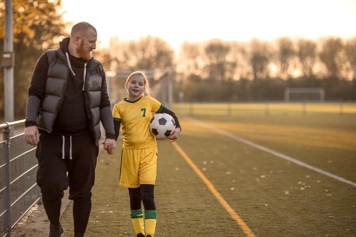 Father and daughter holding hands on soccer field